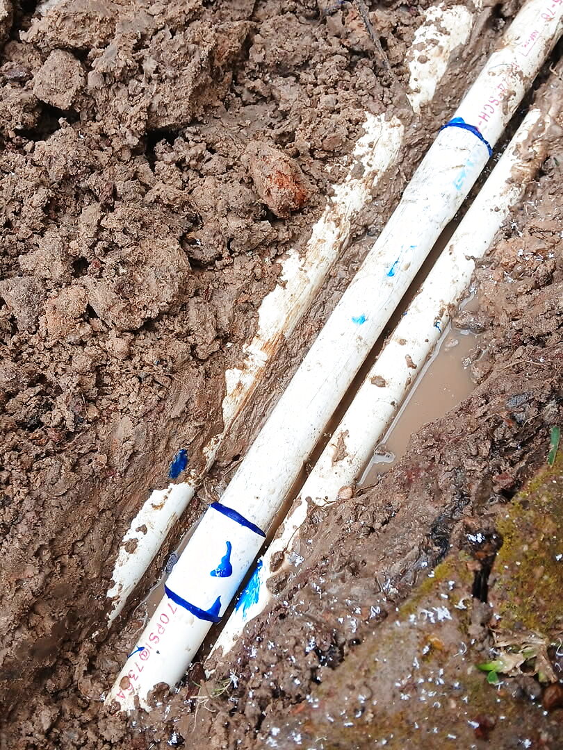 A repaired PVC irrigation line in an open trench in Katy, TX